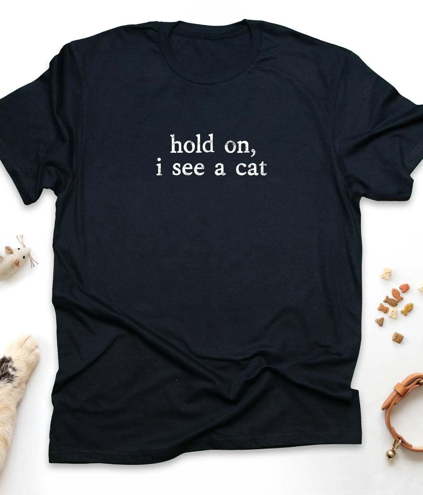 Black funny cat t-shirt with "Hold On, I See A Cat" design, flat lay top view