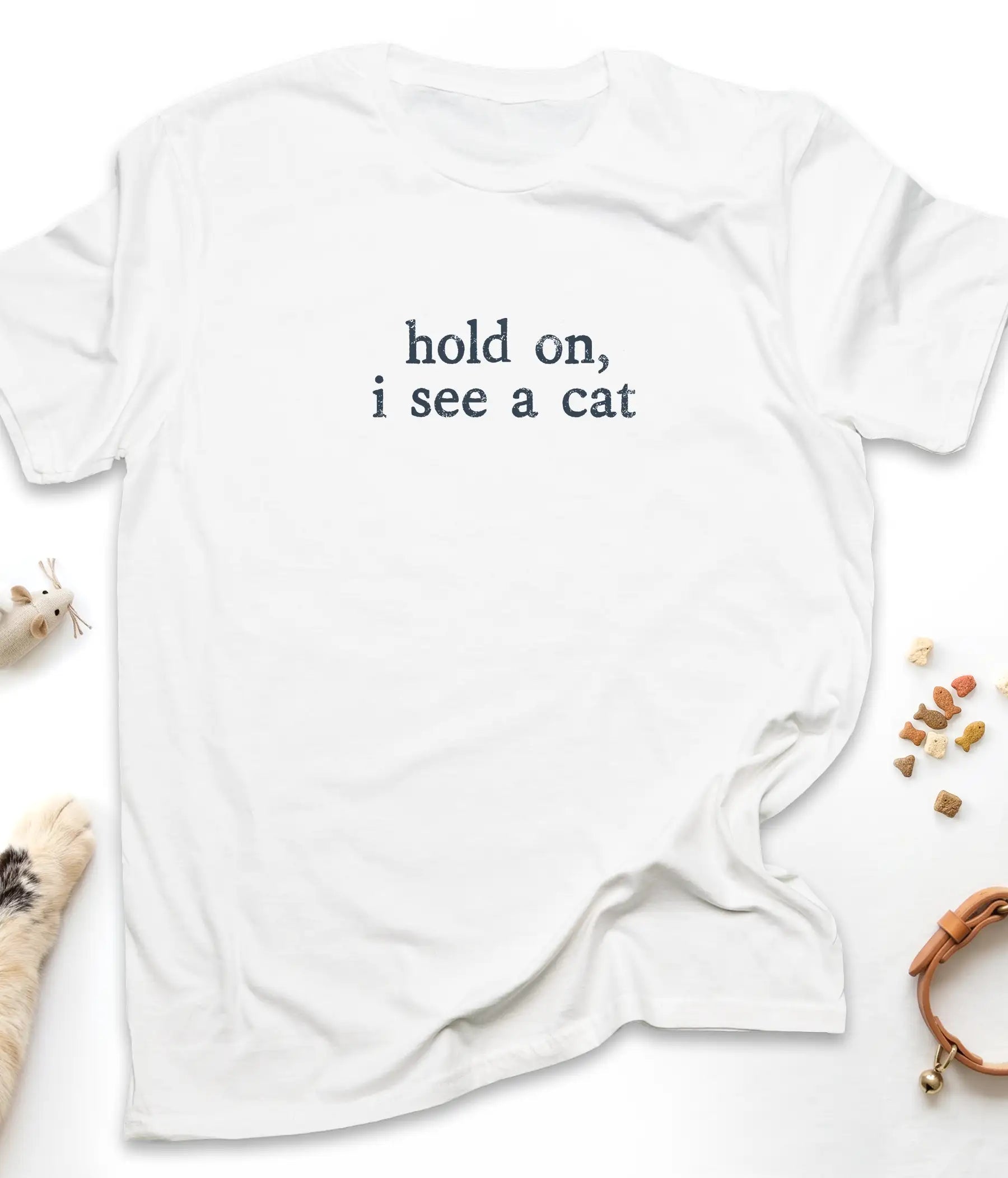 White funny cat t-shirt with "Hold On, I See A Cat" design, flat lay top view