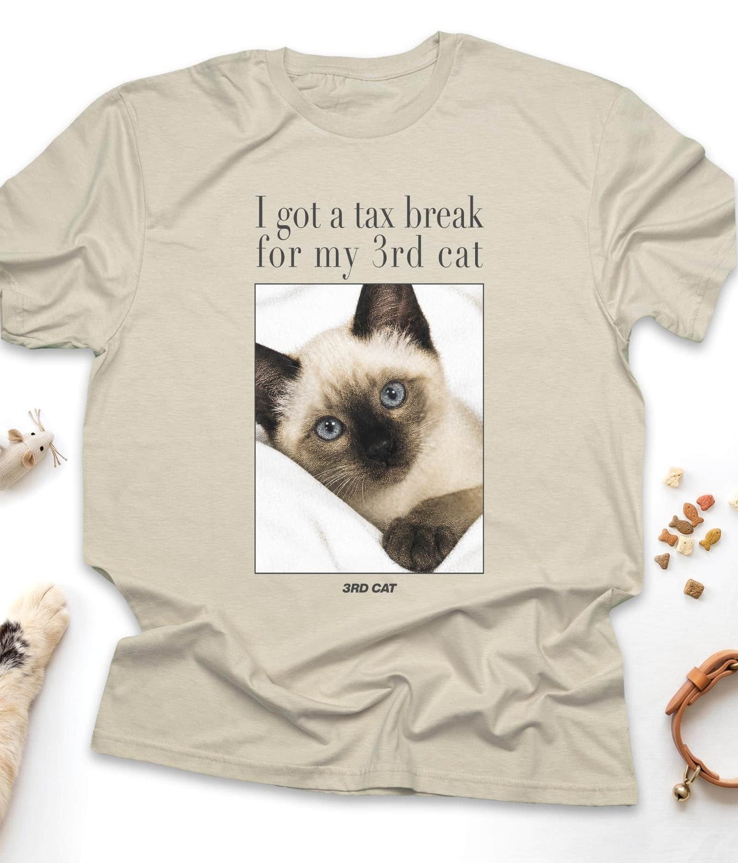 Sand funny cat t-shirt with "I Got A Tax Break For My 3rd Cat (Siamese)" design, flat lay top view