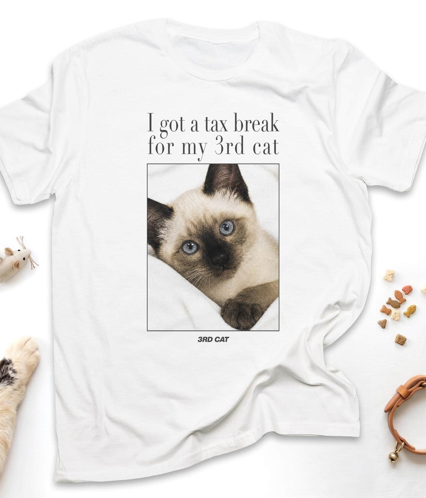 White funny cat t-shirt with "I Got A Tax Break For My 3rd Cat (Siamese)" design, flat lay top view
