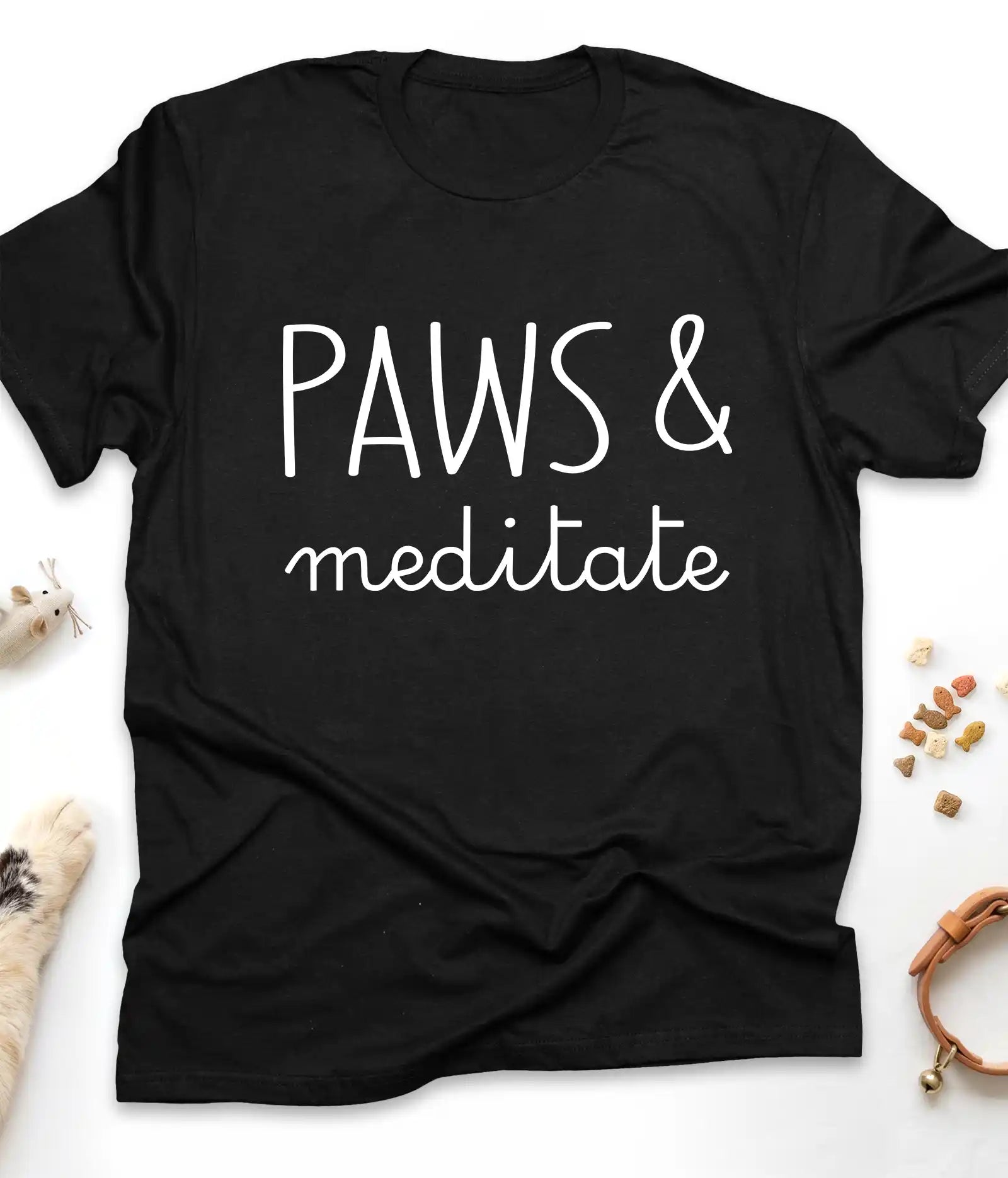 Black funny cat t-shirt with "Paws & Meditate" design, flat lay top view