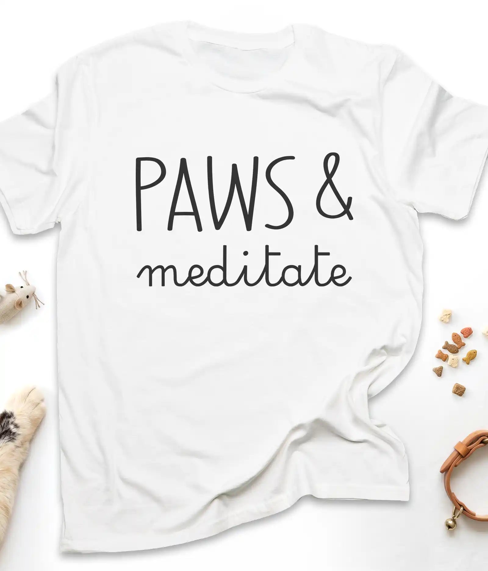 White funny cat t-shirt with "Paws & Meditate" design, flat lay top view