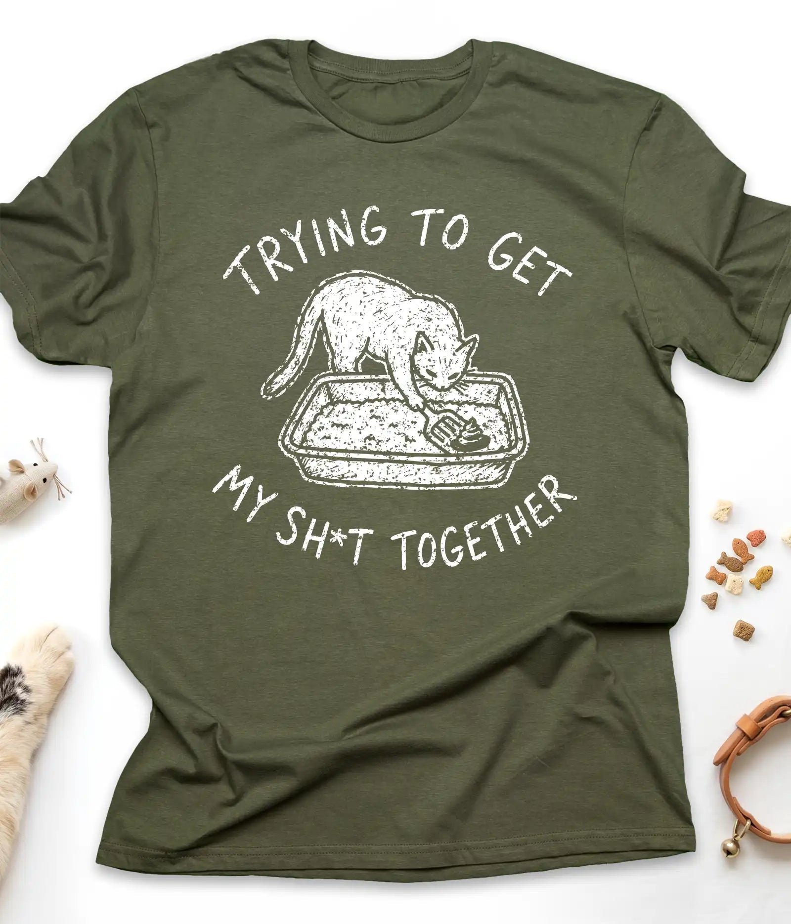 Military Green funny cat t-shirt with "Trying To Get My Shit Together" litter box design, flat lay top view