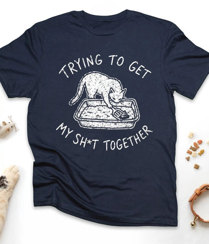 Navy funny cat t-shirt with "Trying To Get My Shit Together" litter box design, flat lay top view