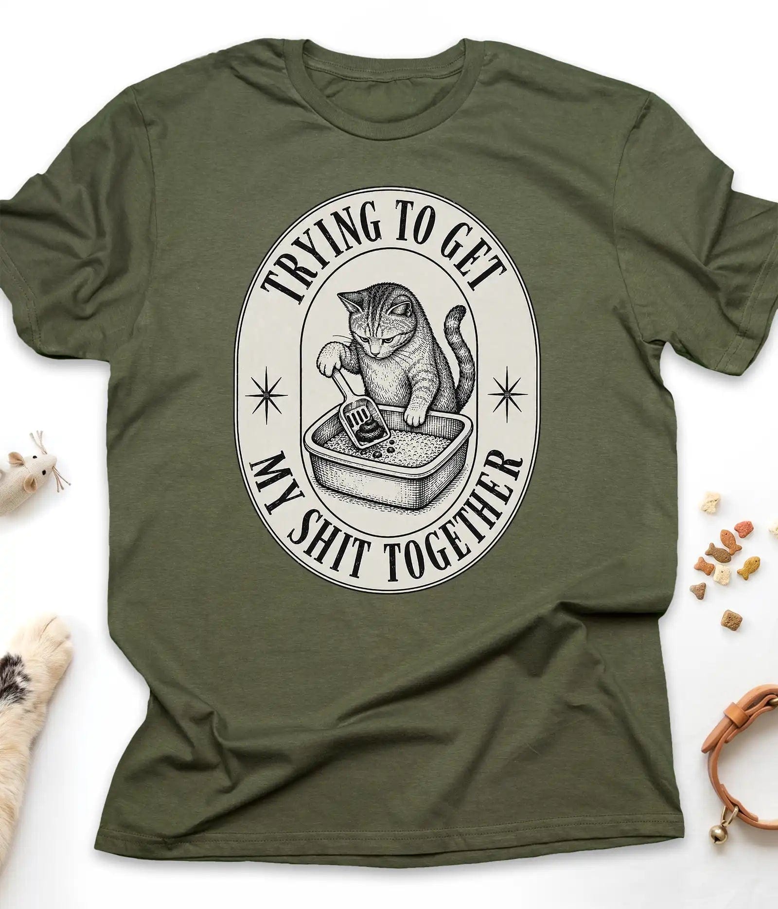 Military Green funny cat t-shirt with a vintage "Trying To Get My Shit Together" litter box design, flat lay top view