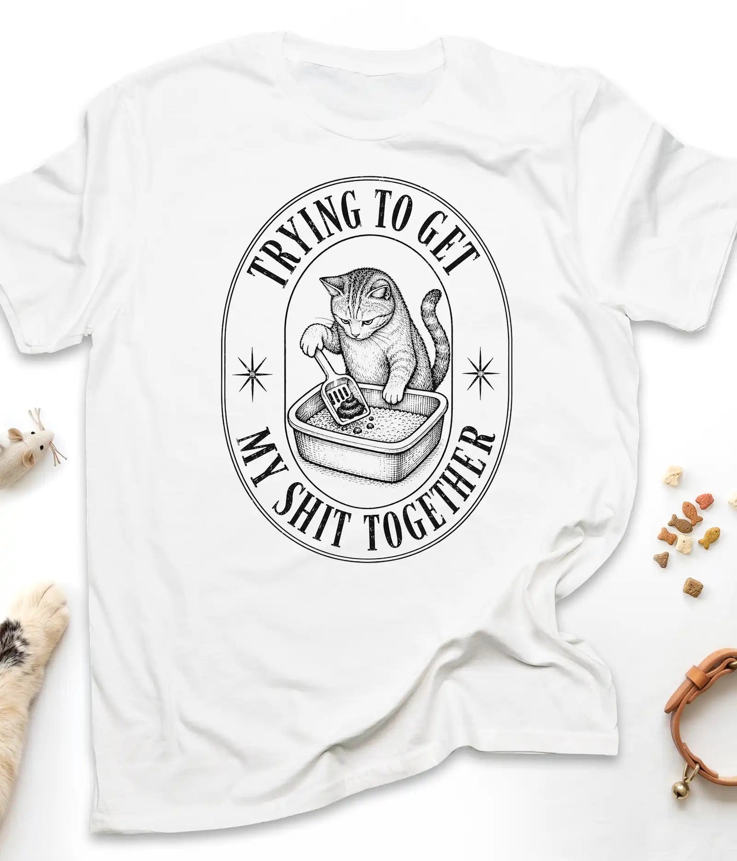 White funny cat t-shirt with a vintage "Trying To Get My Shit Together" litter box design, flat lay top view